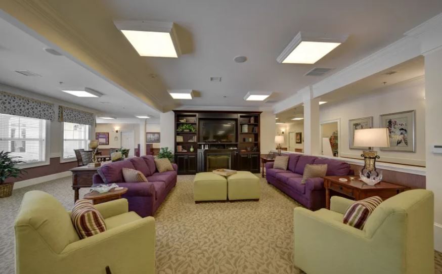 A spacious living room with colorful sofas and a central television setup.