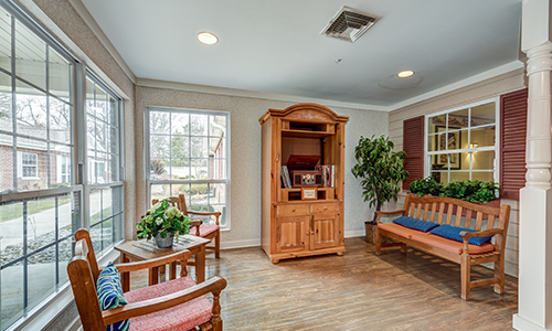 A cozy living room with a wooden cabinet, comfortable seating, and lush plants.