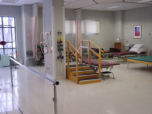 A view of a hospital rehabilitation area featuring beds and a staircase for patient mobility.