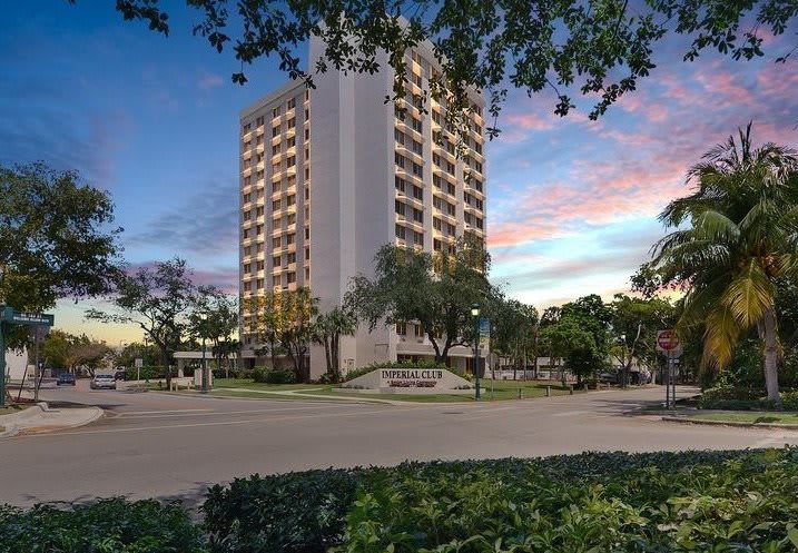A high-rise residential building surrounded by trees at dusk.
