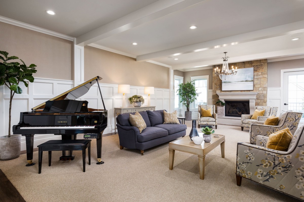 A spacious and elegant living room featuring a grand piano, cozy seating area, and a warm fireplace.