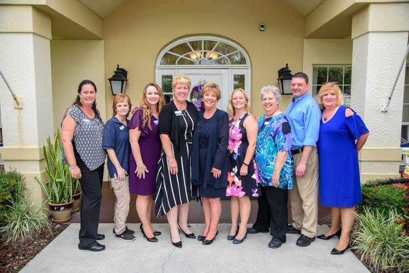 A group of people standing together in formal attire outside a building, smiling for a photo.