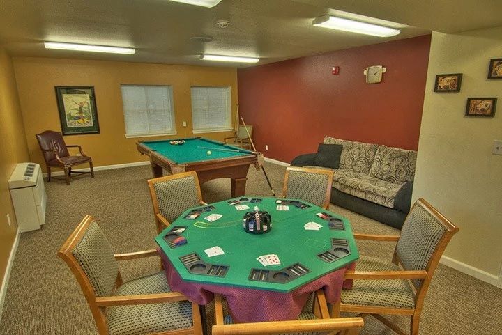A cozy game room featuring a poker table set with cards and chips, alongside a pool table and comfortable seating.