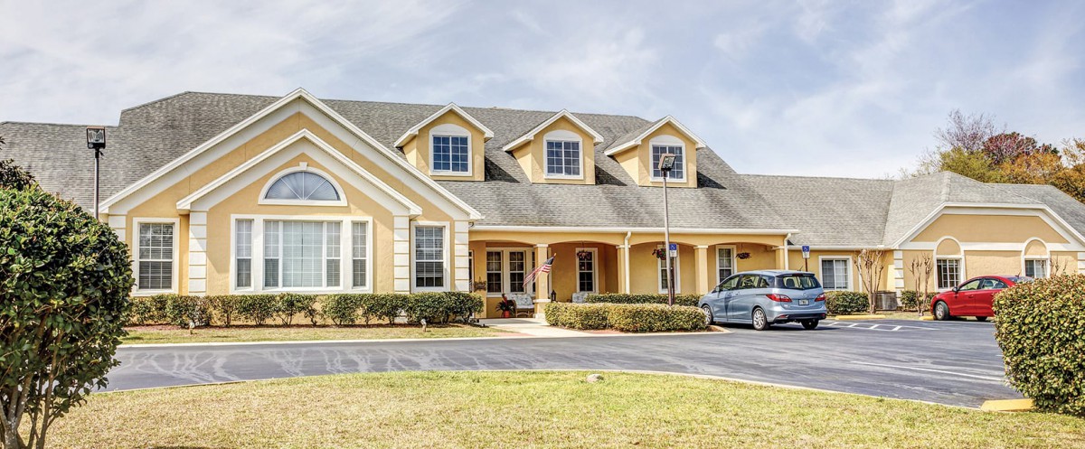 A large suburban house with a driveway and car parked in front.