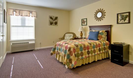 A cozy bedroom with colorful bedding and decorative elements.