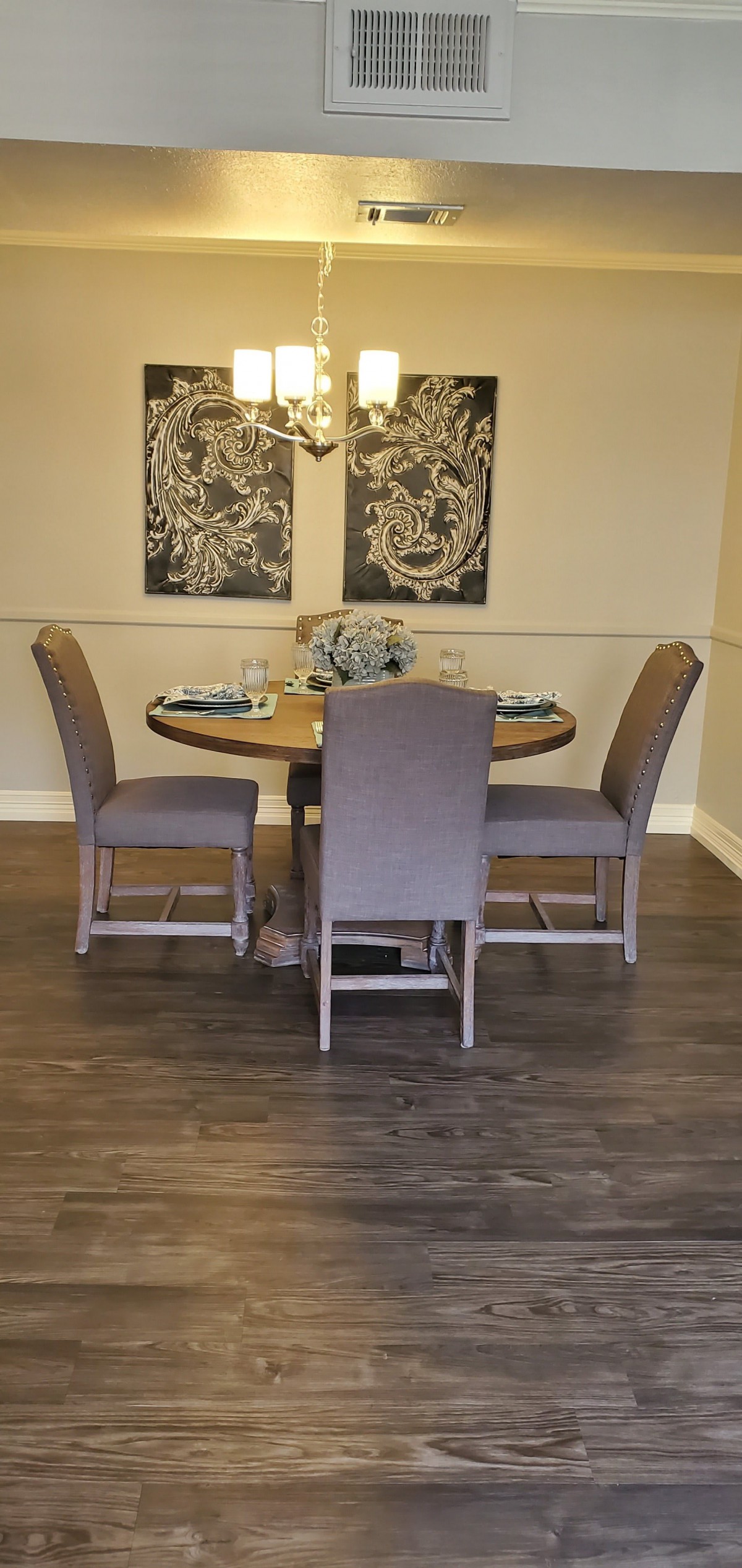 A cozy dining room with a round table and four upholstered chairs, adorned with wall art.
