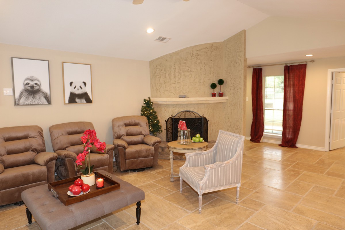 A cozy living room with armchairs, a coffee table, and a fireplace, featuring elegant decor and artwork.