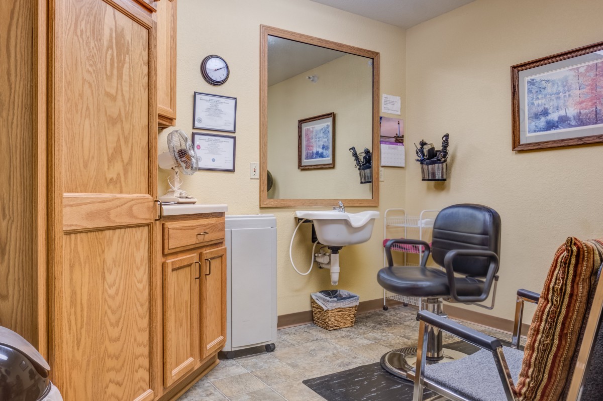 A cozy hair salon room with a barber chair, mirror, and sink.