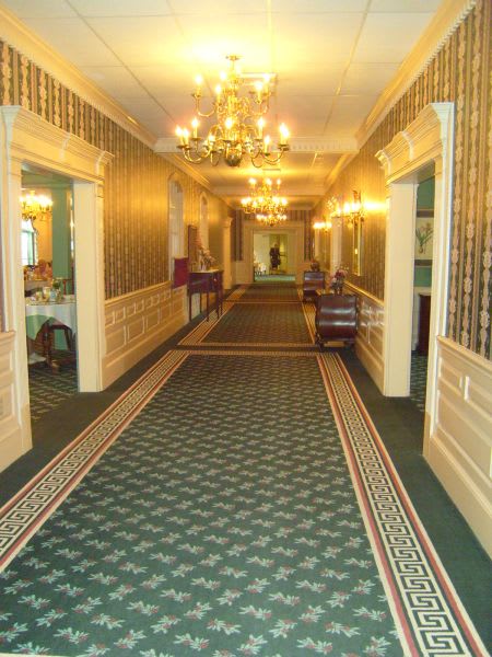 A well-lit hallway with chandeliers and patterned carpet.
