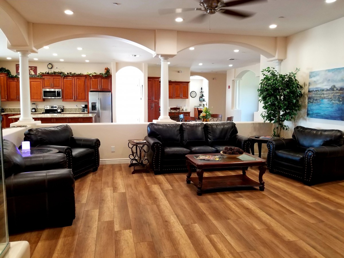 Spacious open-concept living room with leather sofas and a view of the kitchen.