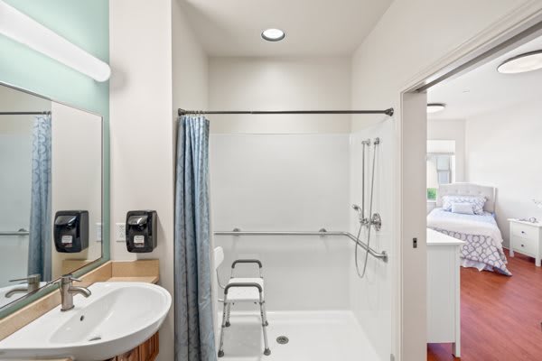 An accessible bathroom designed with safety features, including grab bars and a shower seat.