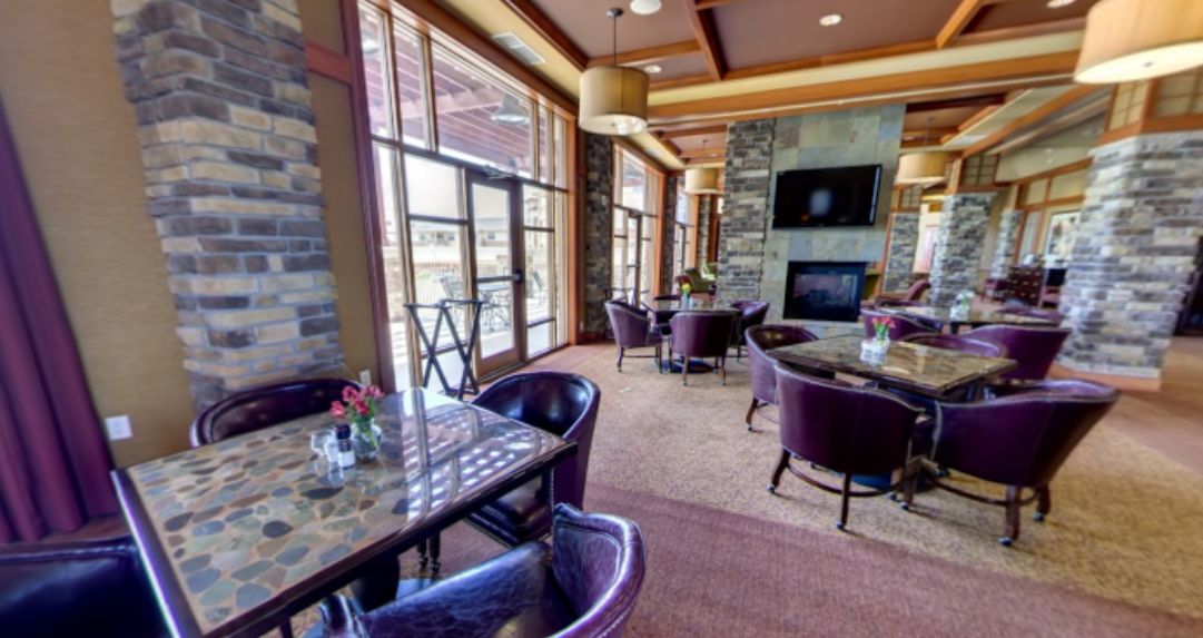 A modern dining area with purple chairs, tables, and a cozy fireplace.