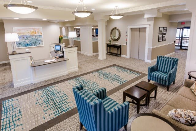 A welcoming hotel lobby with a reception desk, comfortable seating area, and elevator access.