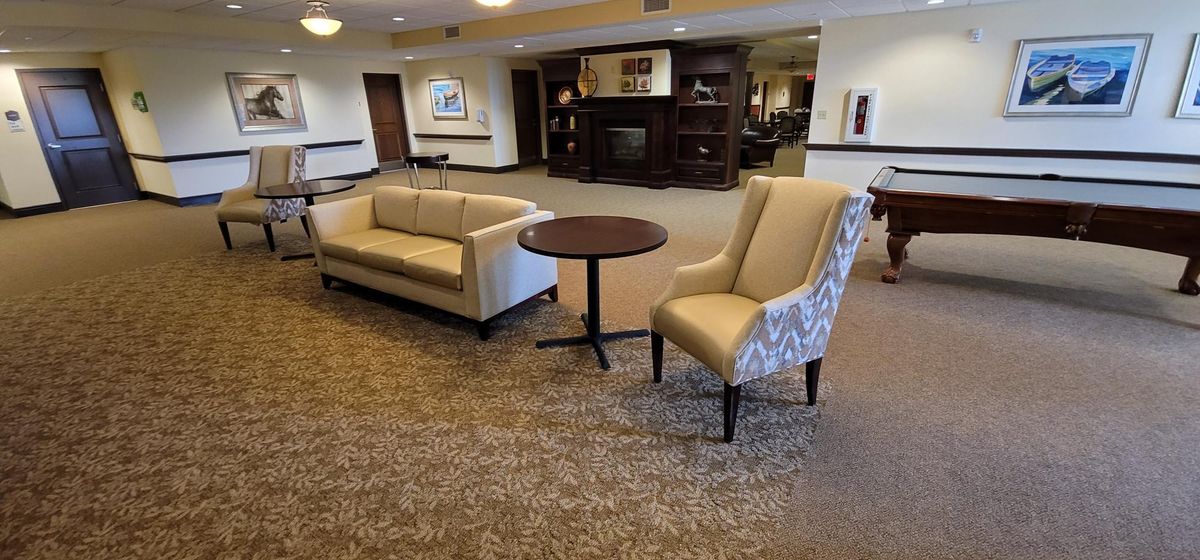 A cozy lobby area with a sofa, armchair, and table on a carpeted floor.