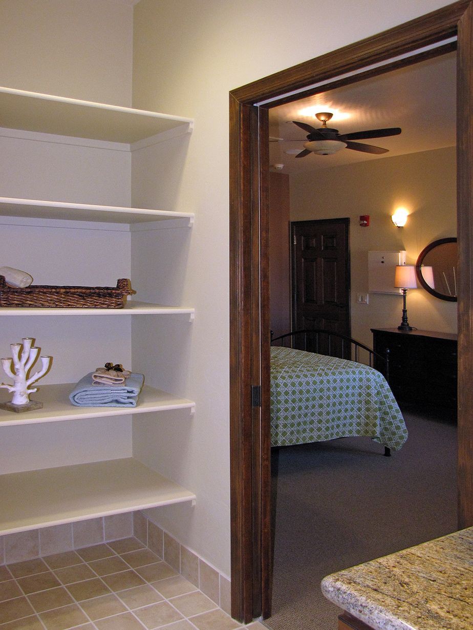A cozy bedroom with a view of decorative shelves and a bed with a checkered duvet.