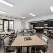 A modern dining area with tables and chairs, featuring an adjacent kitchen space.