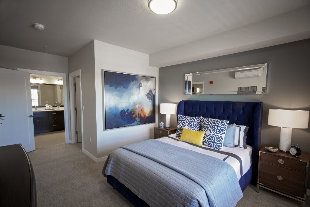 A modern bedroom featuring a large artwork above the bed, with stylish bedding and decor.