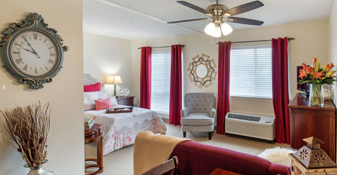 A cozy bedroom featuring red curtains, a comfortable bed, and stylish decor.