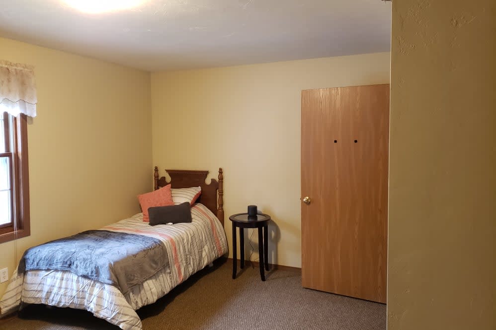 A minimalist bedroom with a single bed and a small table.