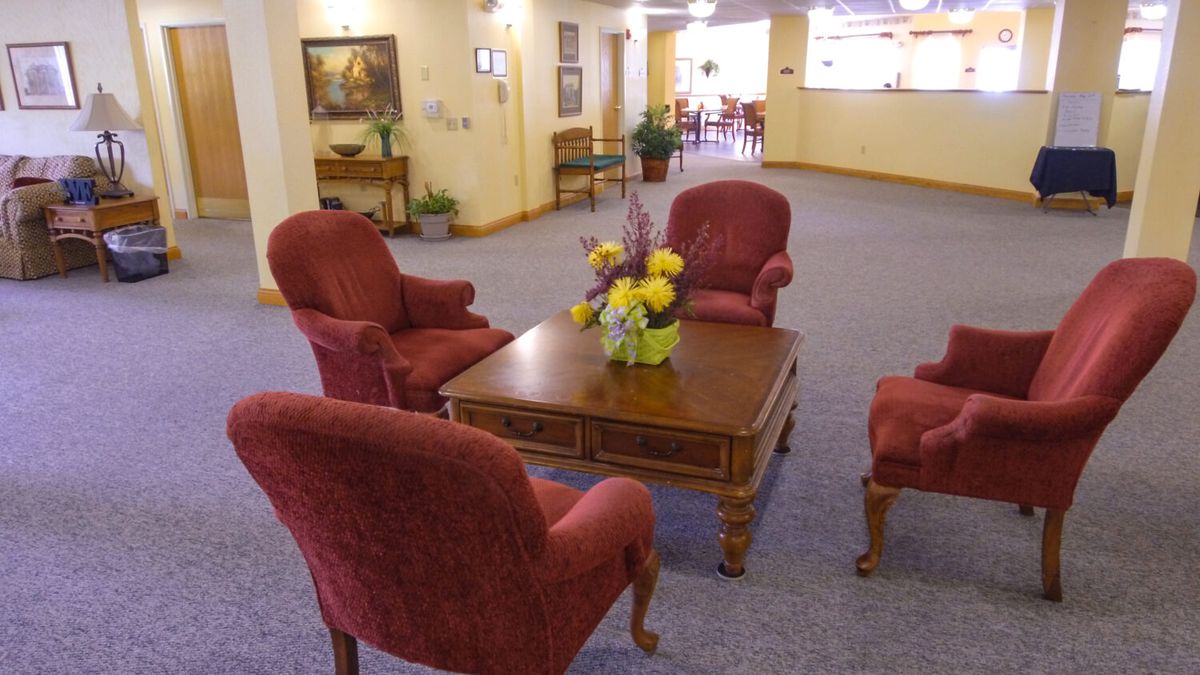A cozy lobby with red upholstered chairs and a wooden table featuring a flower arrangement.