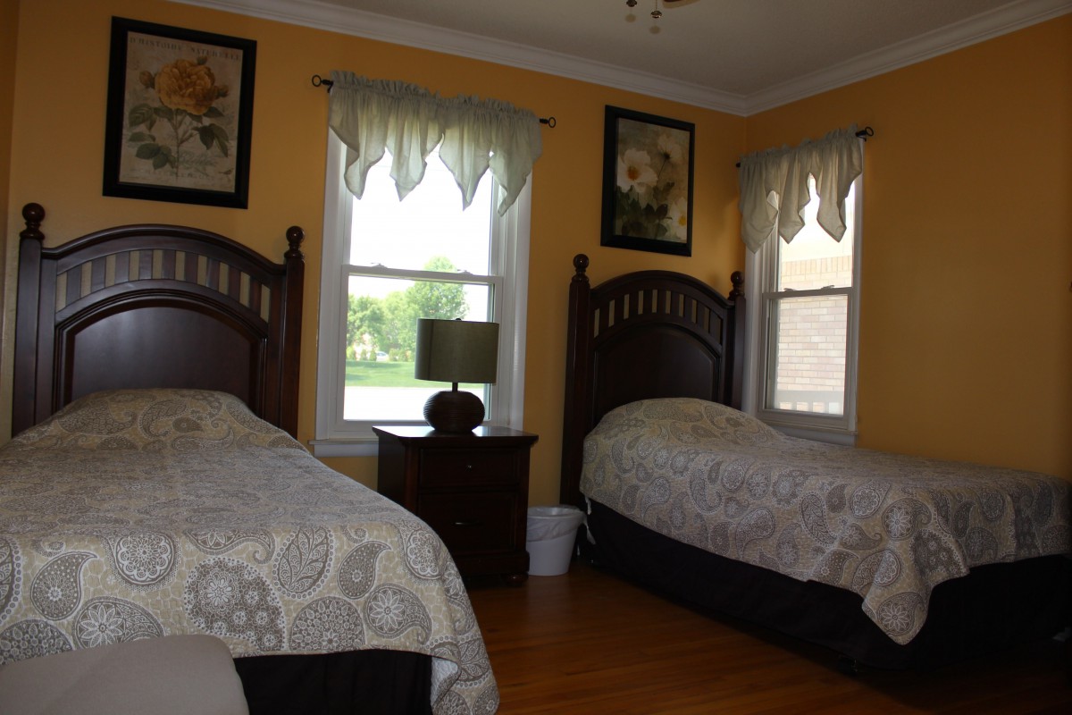 A cozy bedroom with twin beds and large windows.