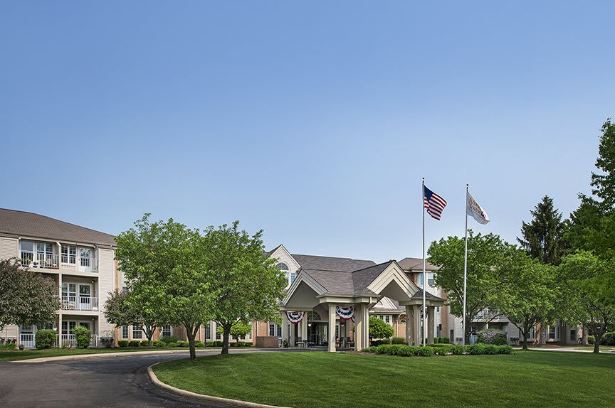 A building with flags and well-maintained landscaping on a clear day.