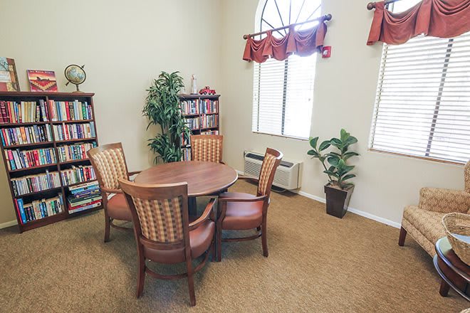 A cozy reading room with a round table, surrounded by chairs and bookshelves.
