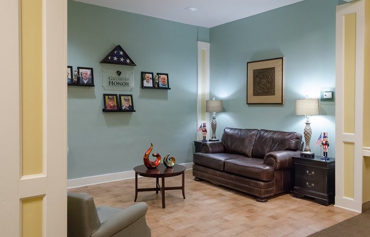 A cozy living room with a leather sofa, lamps, and decorative wall art.