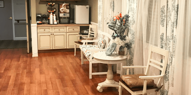 A cozy living room with vintage-style furniture, wooden flooring, and decorative flowers.