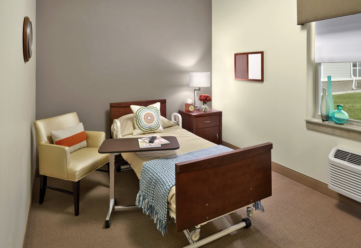 A cozy hospital room with a bed, chair, and side table.
