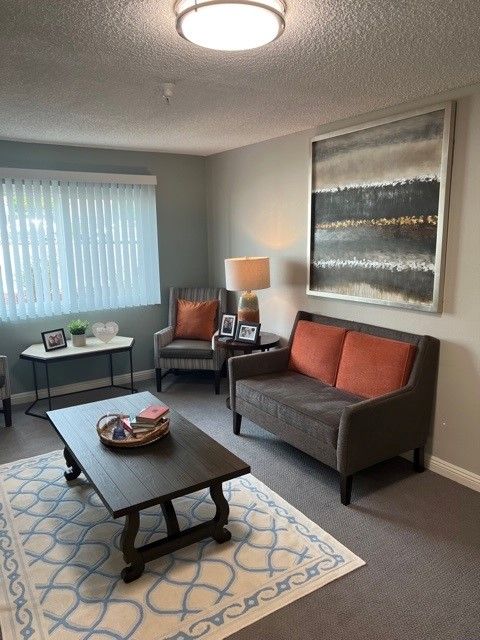 A cozy living room featuring a sofa, armchairs, and a coffee table with modern decor.