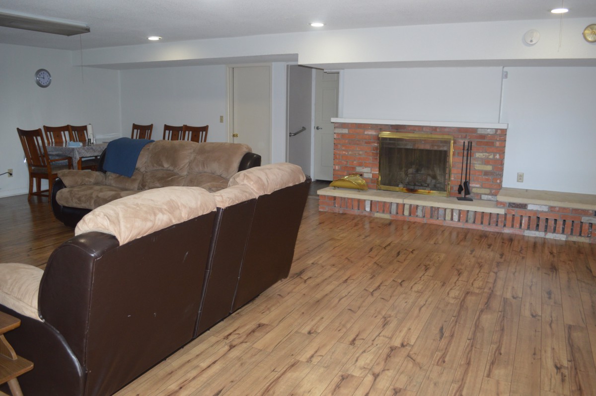 A cozy living room featuring a sofa and a fireplace with wood flooring.