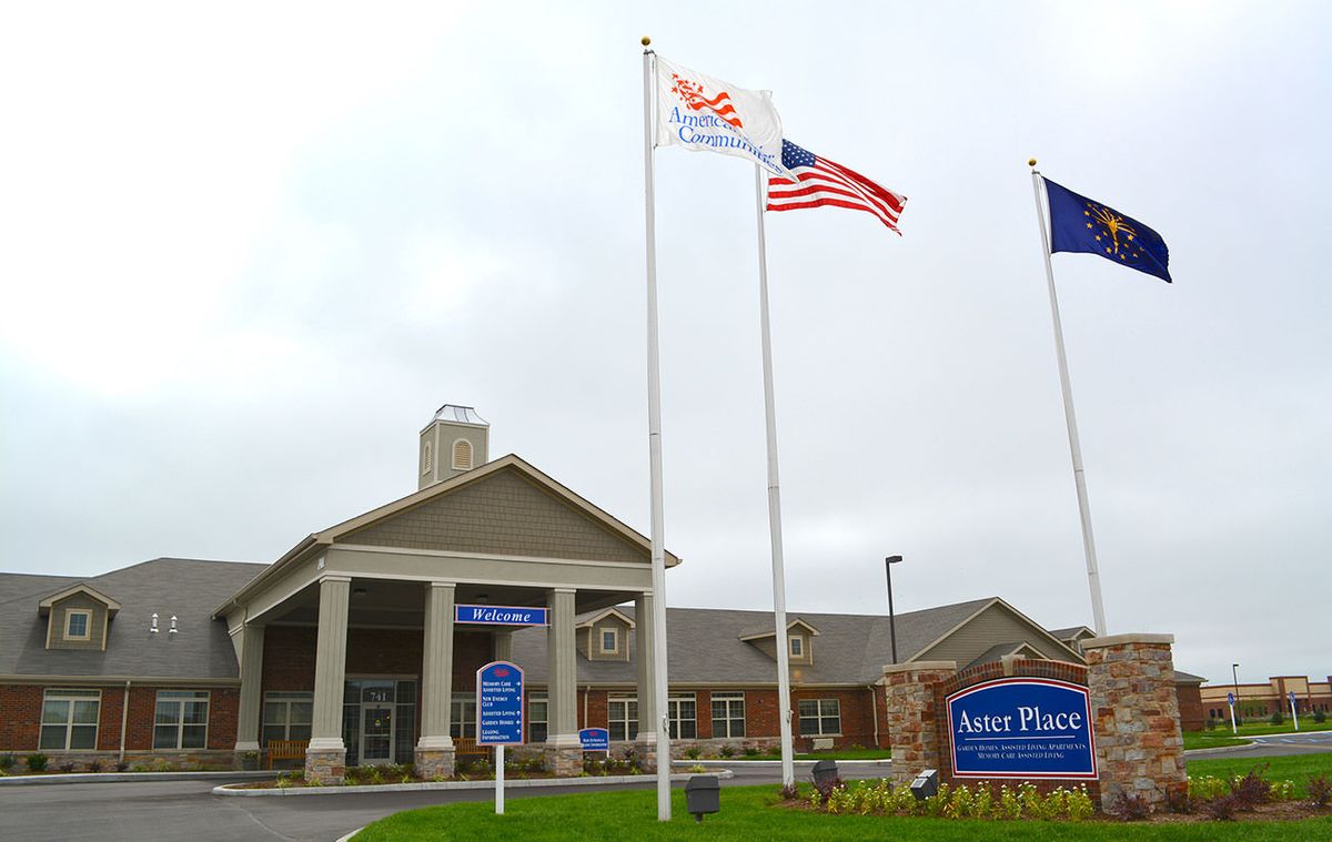 A building entrance with multiple flags and a sign on a cloudy day.