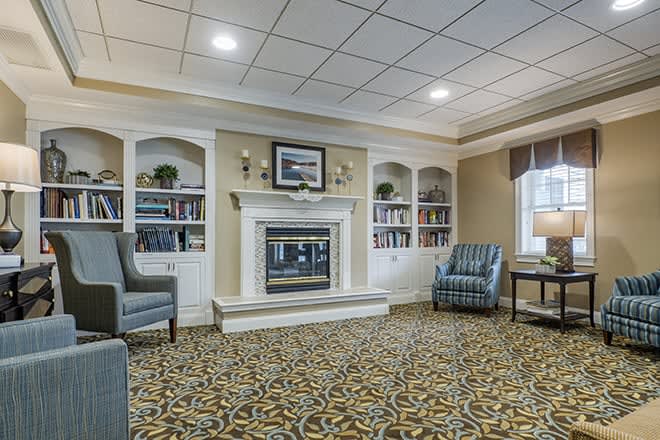 A cozy living room featuring a fireplace, armchairs, and built-in bookshelves.