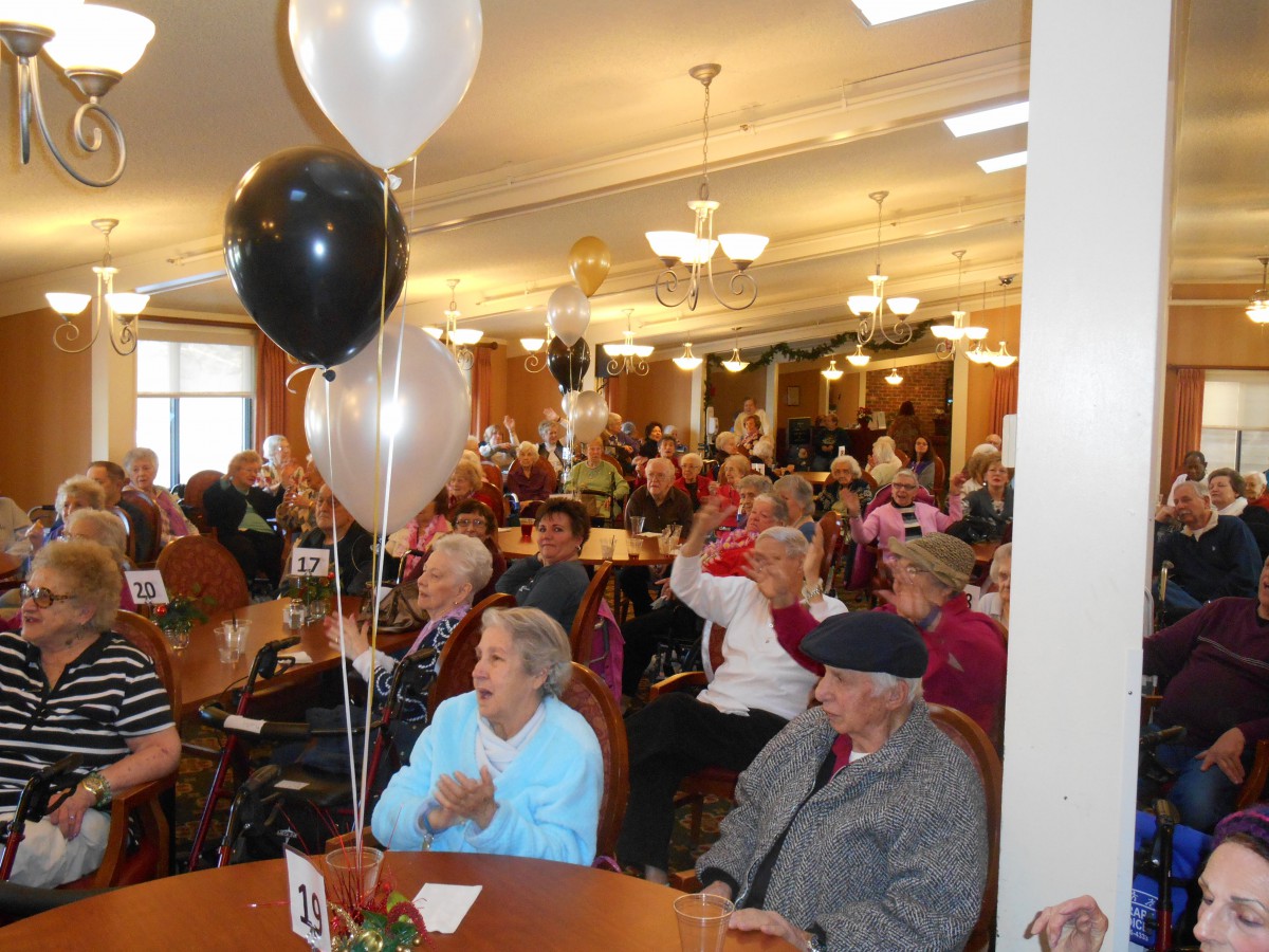 A lively gathering of senior citizens enjoying a festive celebration with balloons and decorations.