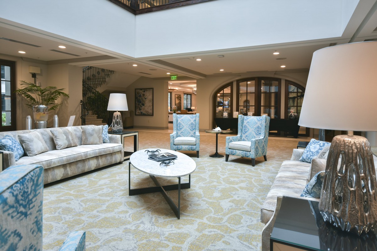 A modern lobby seating area with comfortable chairs and sofas around a central coffee table.