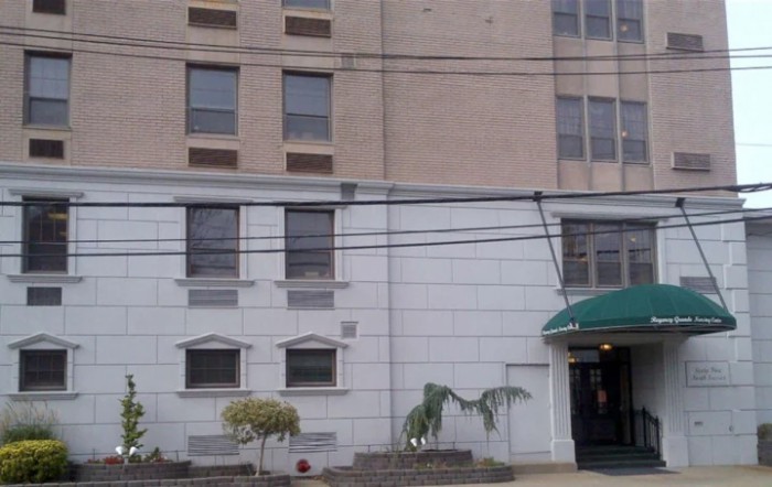 A city building with multiple windows and a green awning over the entrance.