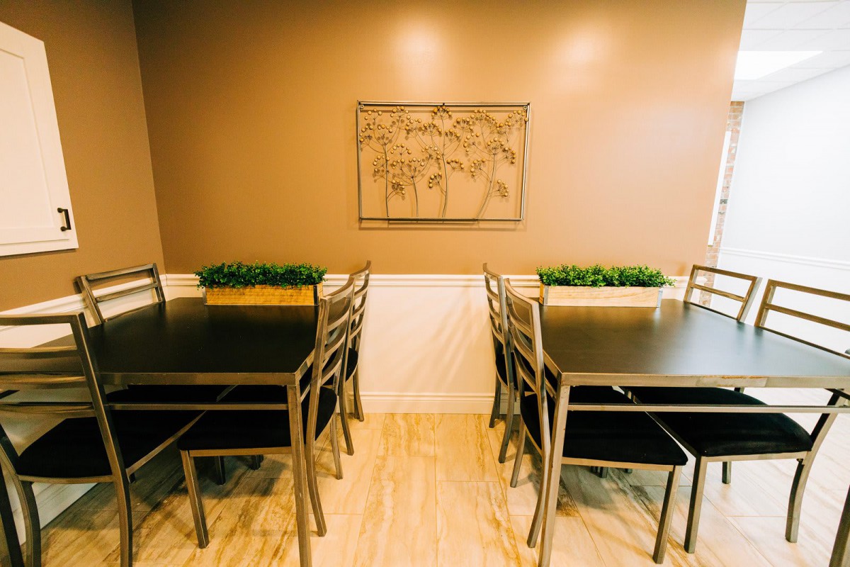 A cozy dining space with tables, chairs, and decorative plants.