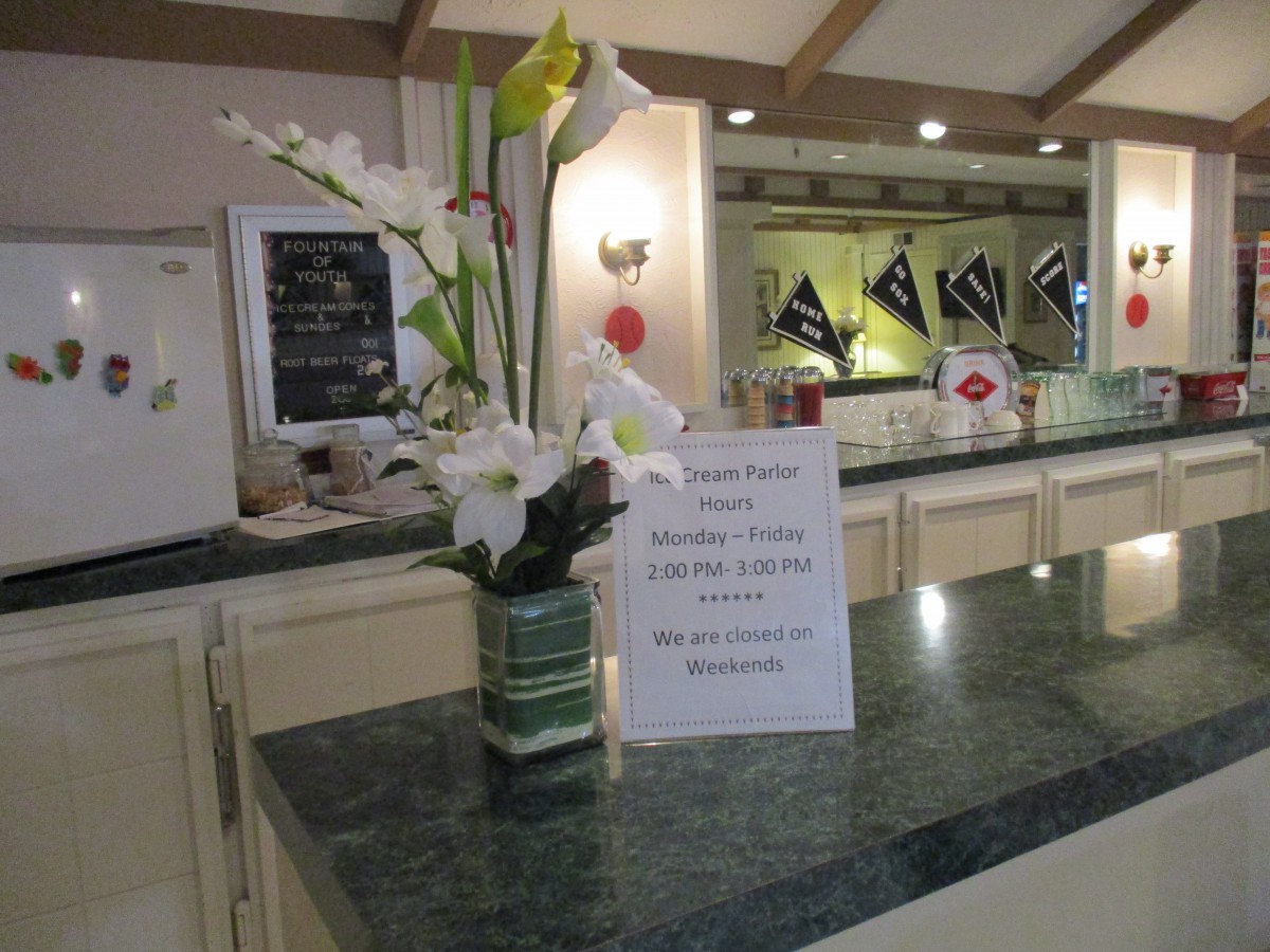 A hotel reception desk with a sign and floral arrangement.