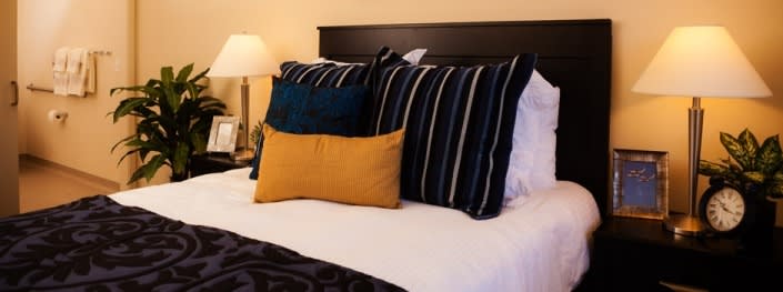 A neatly made bed with striped and solid color pillows, creating a cozy and stylish atmosphere.