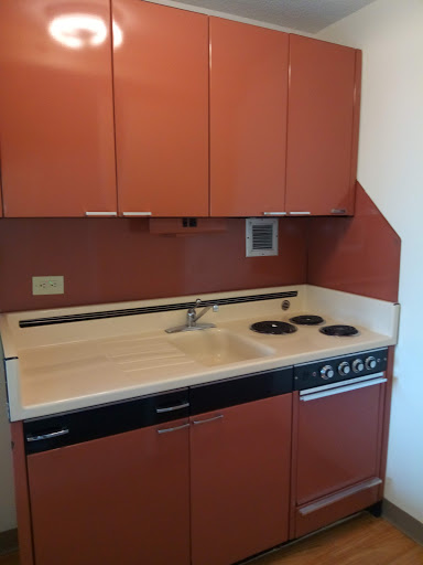 A compact modern kitchen featuring a sink, stove, and cabinetry in warm tones.