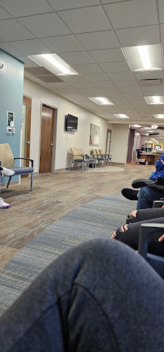 A waiting room in a healthcare facility with several chairs and patients seated.