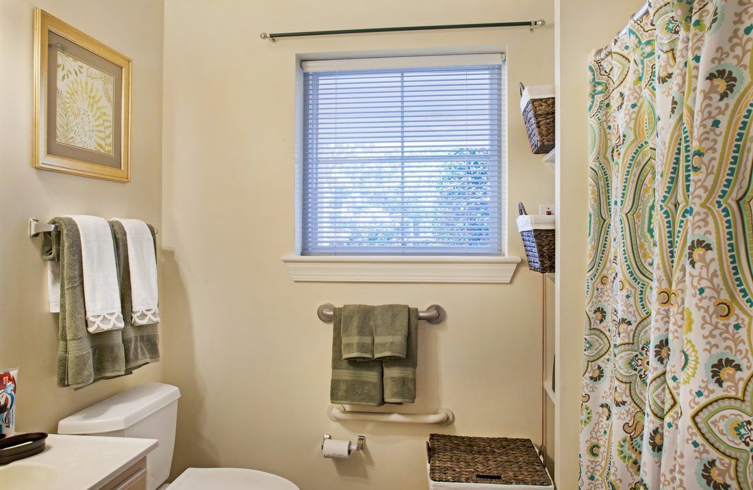 A well-organized bathroom with a window, towels, and a decorative shower curtain.