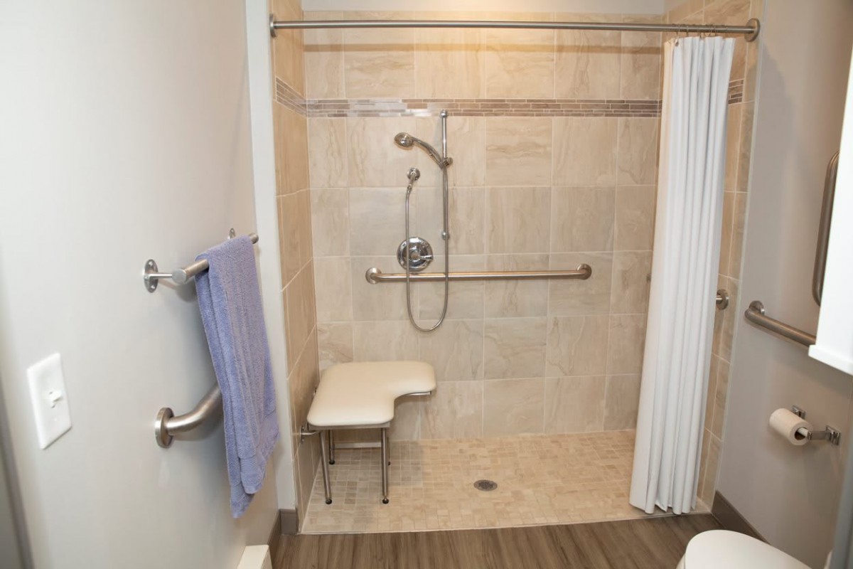 An accessible shower with a chair and grab bars.