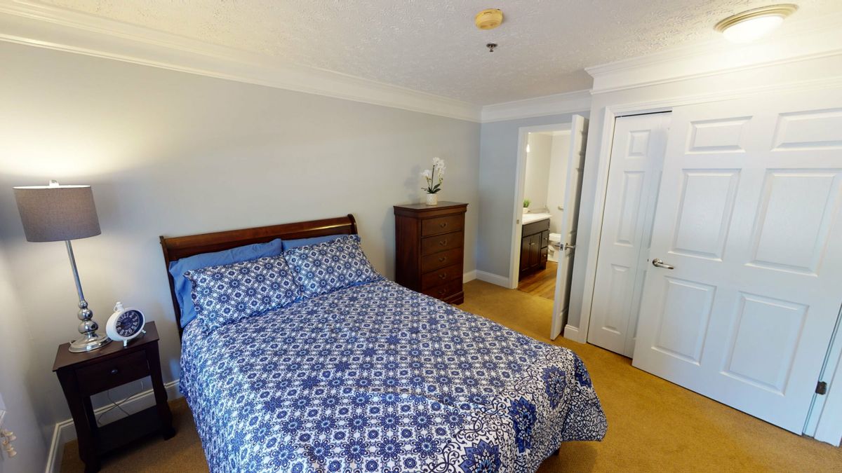 A cozy bedroom with a patterned bedspread and wooden furniture.