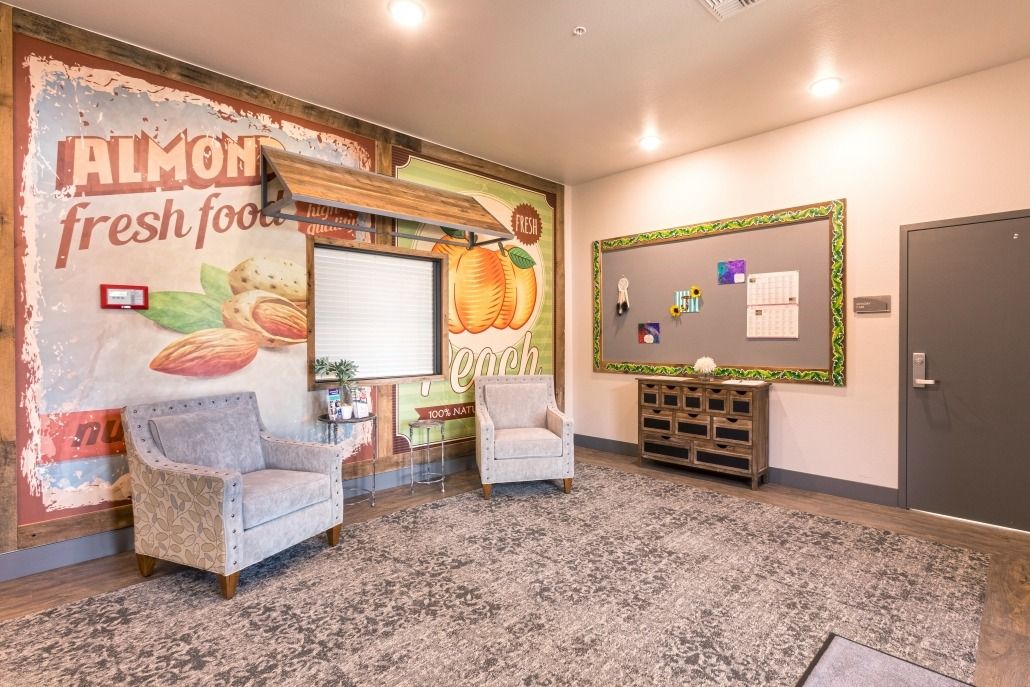 A cozy room with two armchairs, a bulletin board, and a colorful mural on the wall.