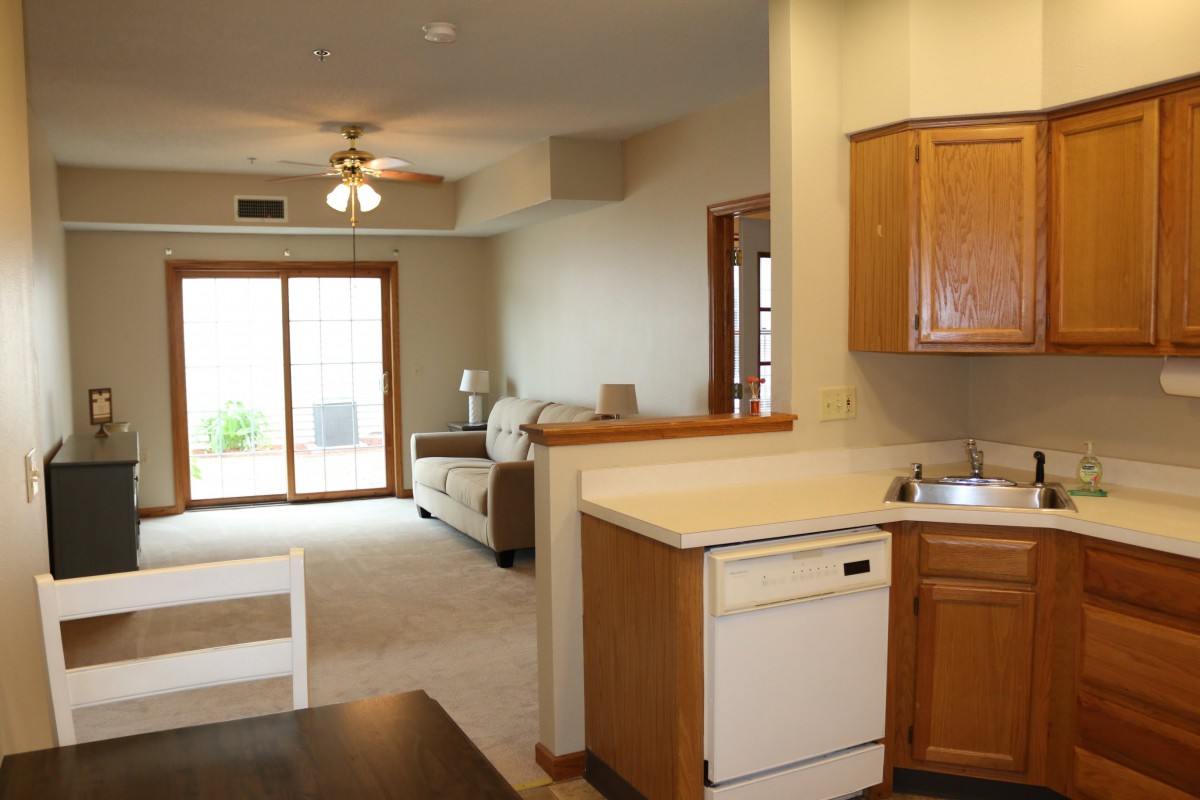An open-concept kitchen and living room with wood cabinetry and a sliding glass door.