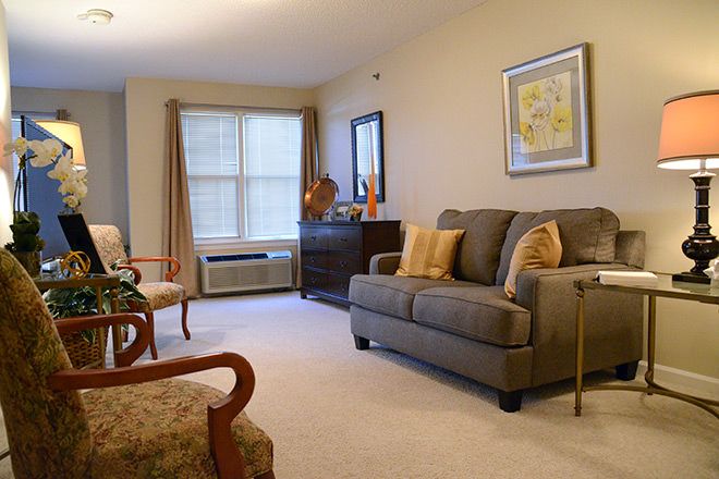 A cozy living room with a sofa and armchairs, decorated with neutral tones and artwork.
