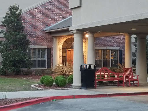 The welcoming entrance of a building featuring outdoor seating and well-kept landscaping.