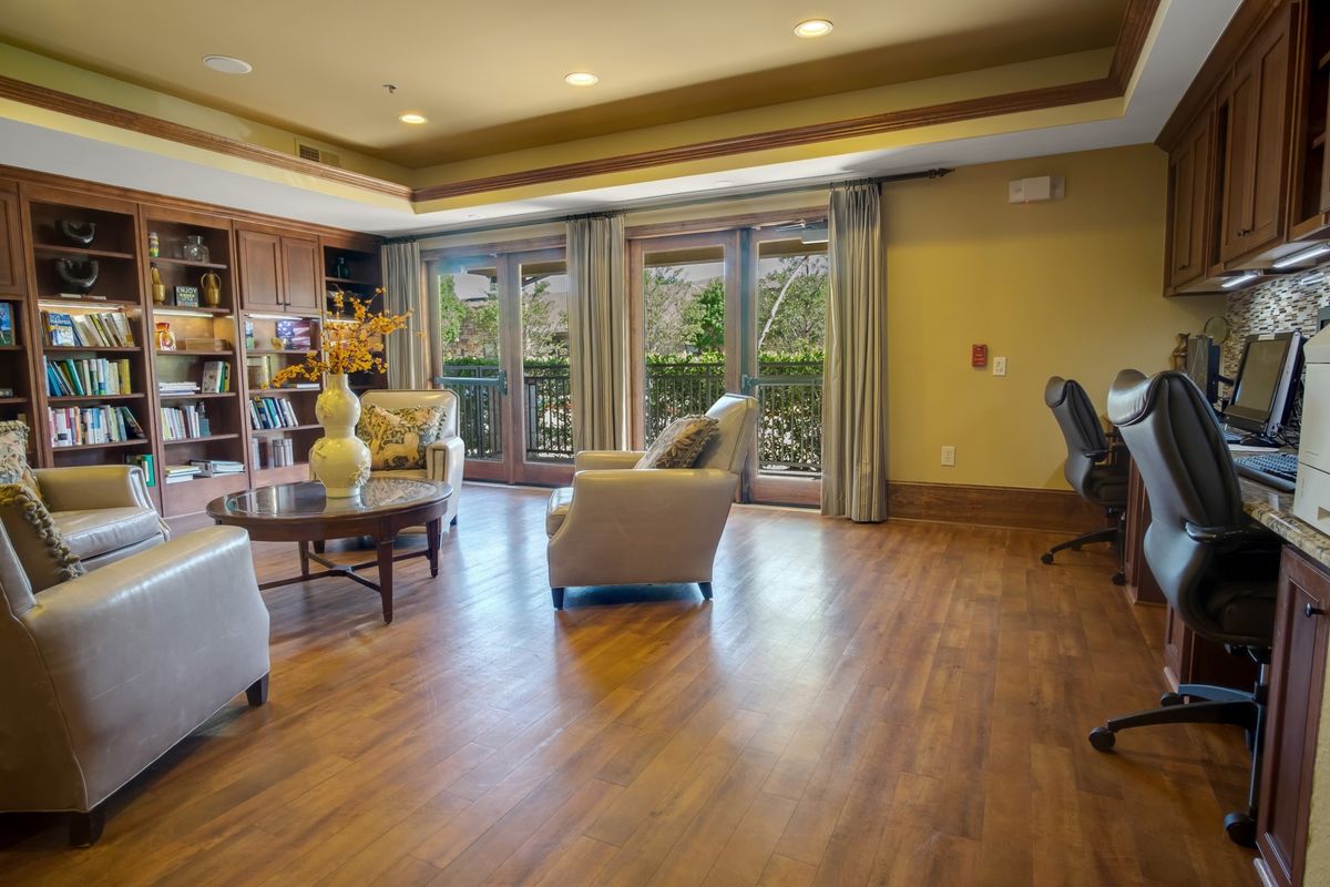 A spacious living room with wood flooring and large windows letting in natural light.
